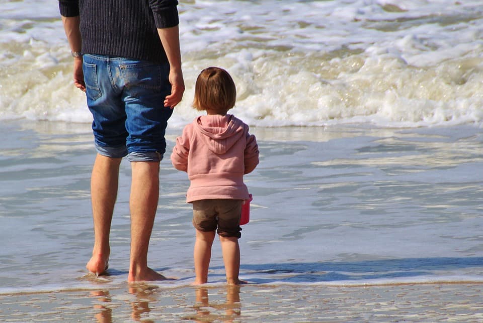 Pai e criança na praia.